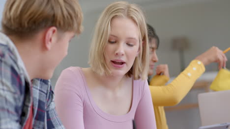 Happy-diverse-group-of-teenage-friends-studying-at-table-with-tablets-at-home,-slow-motion