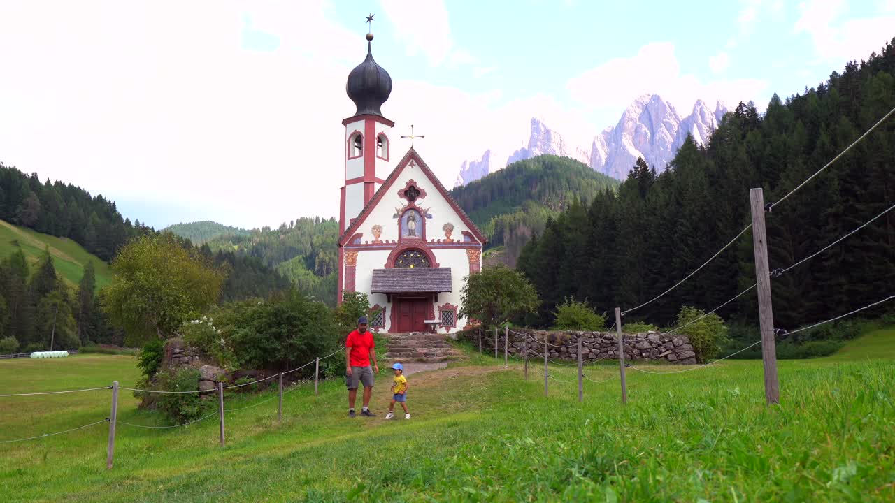 Turistas saludando a la iglesia de Santa Magdalena en Val di Funes, Dolomitas, Italia
