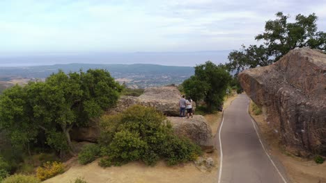 aerial of a man and woman standing on a rock overlooking santa barbara california