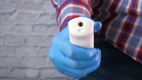 person holding a non-contact thermometer in blue gloves