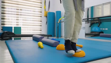 a young girl doing rehabilitation balance exercises while supported by a harness at physiotherapy