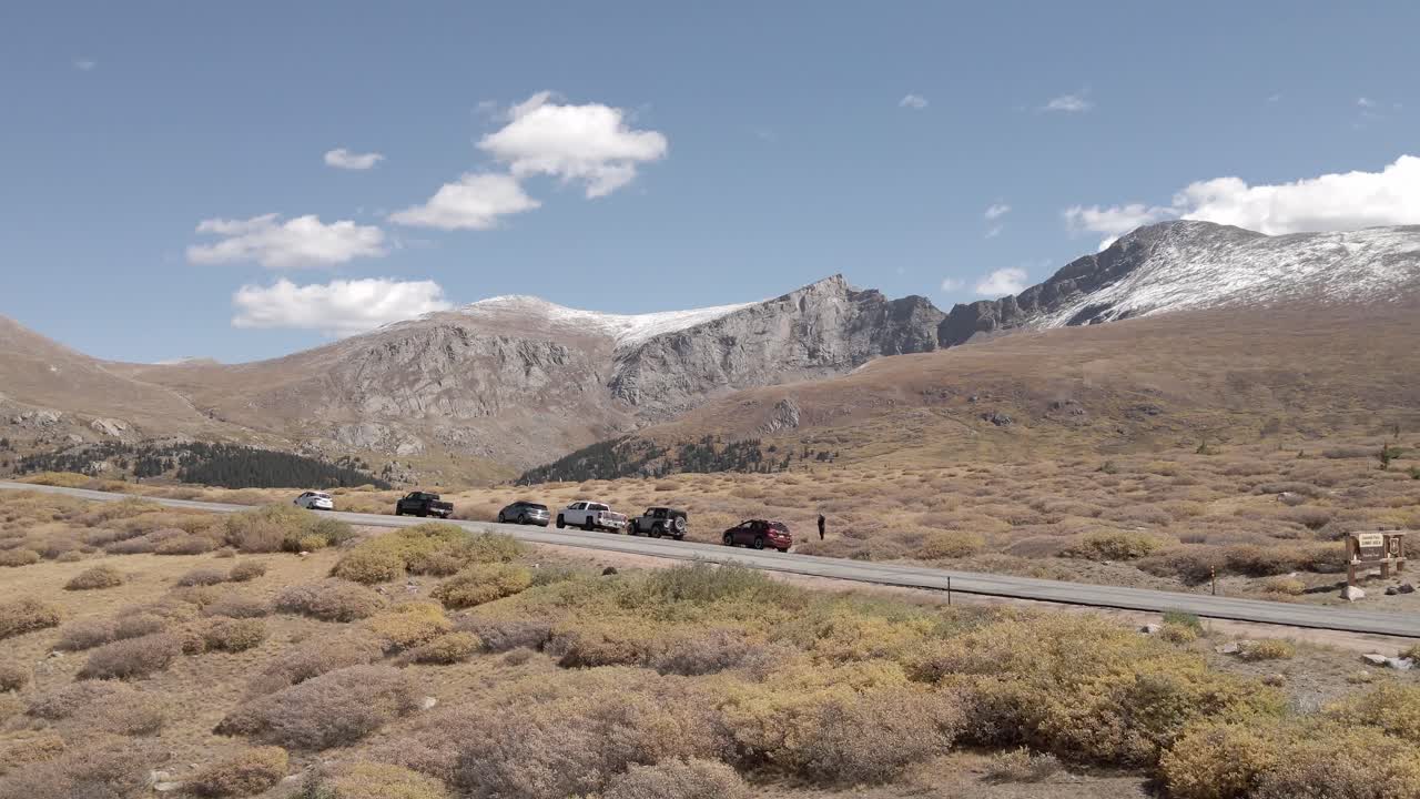View of Mount Blue Sky and Mount Bierstdt from over the Guanella Pass Road with parked vehicles along the highway. Filmed in Colorado during the fall, aerial view with panning movement to the right.