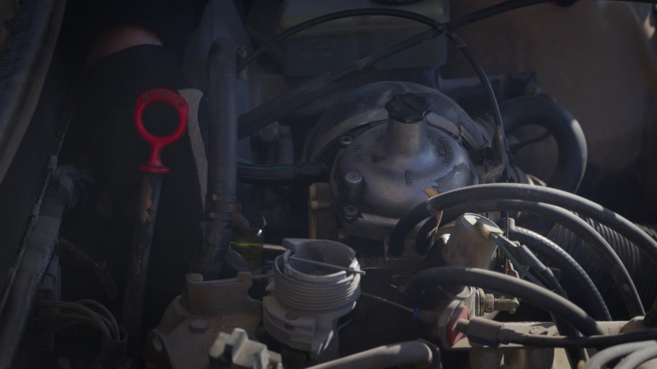 A mechanic adjusts the carburetor on a classic car engine during maintenance. Close-up of hands-on tuning, mechanical repair and vintage vehicle servicing.