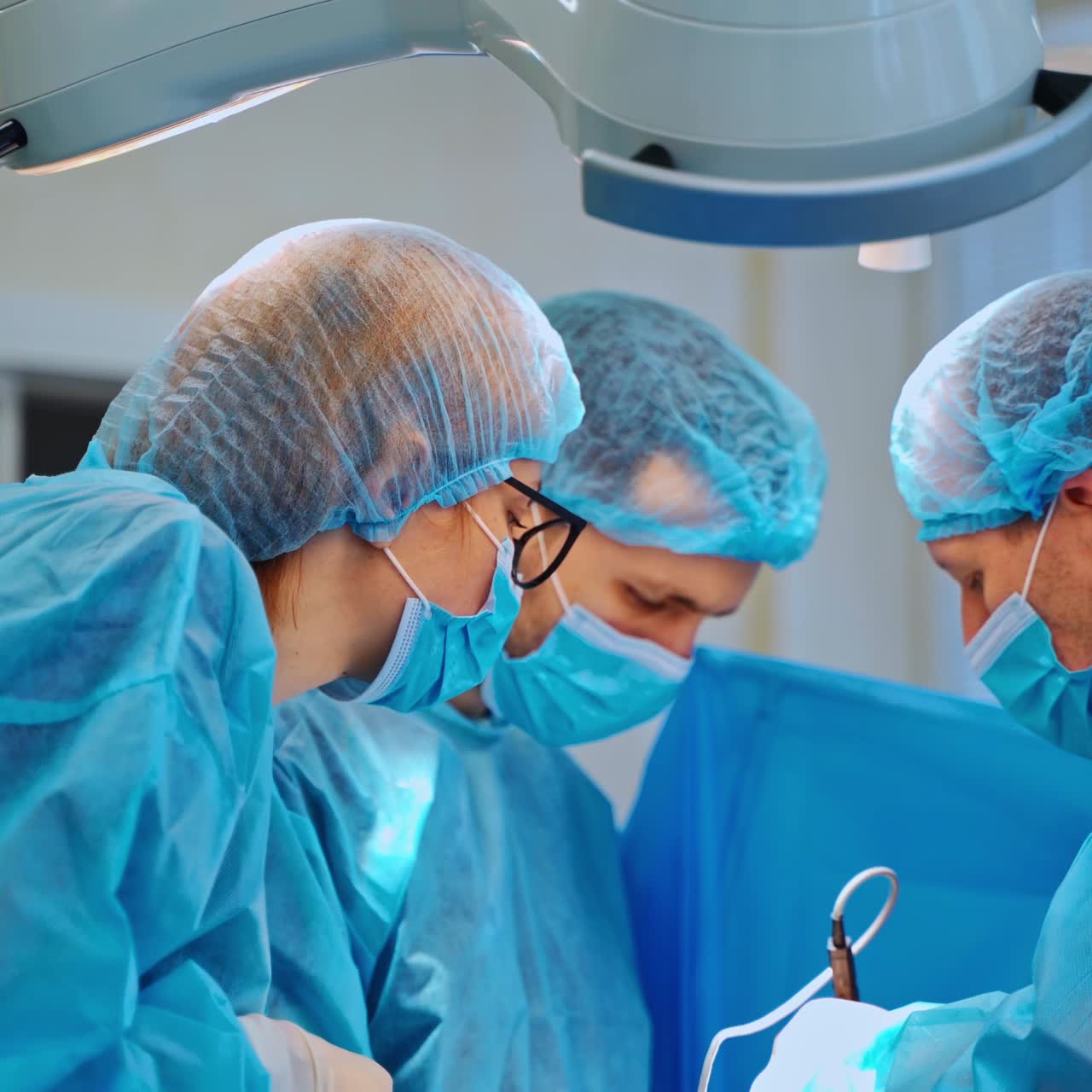 Three doctors in surgical masks. Teamwork of surgeons in blue medical uniform perform an operation in the hospital.
