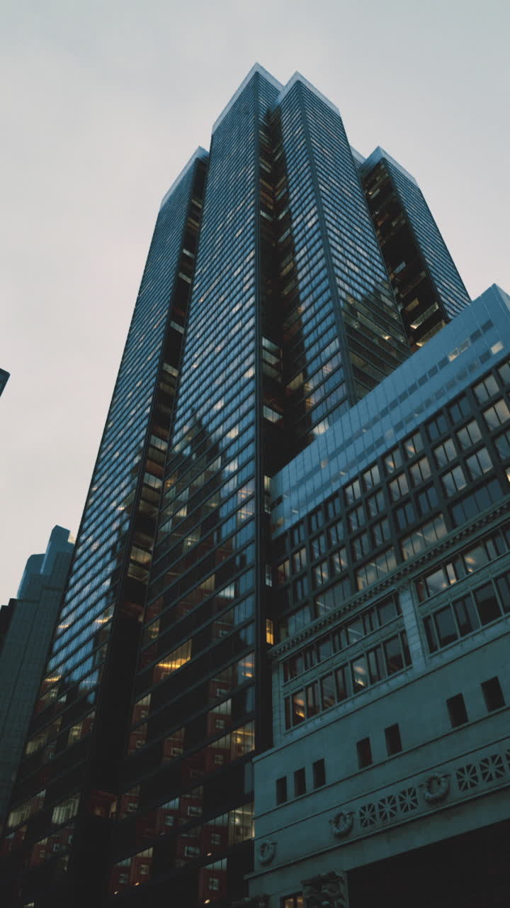 Tall skyscraper surrounded by city buildings under cloudy sky