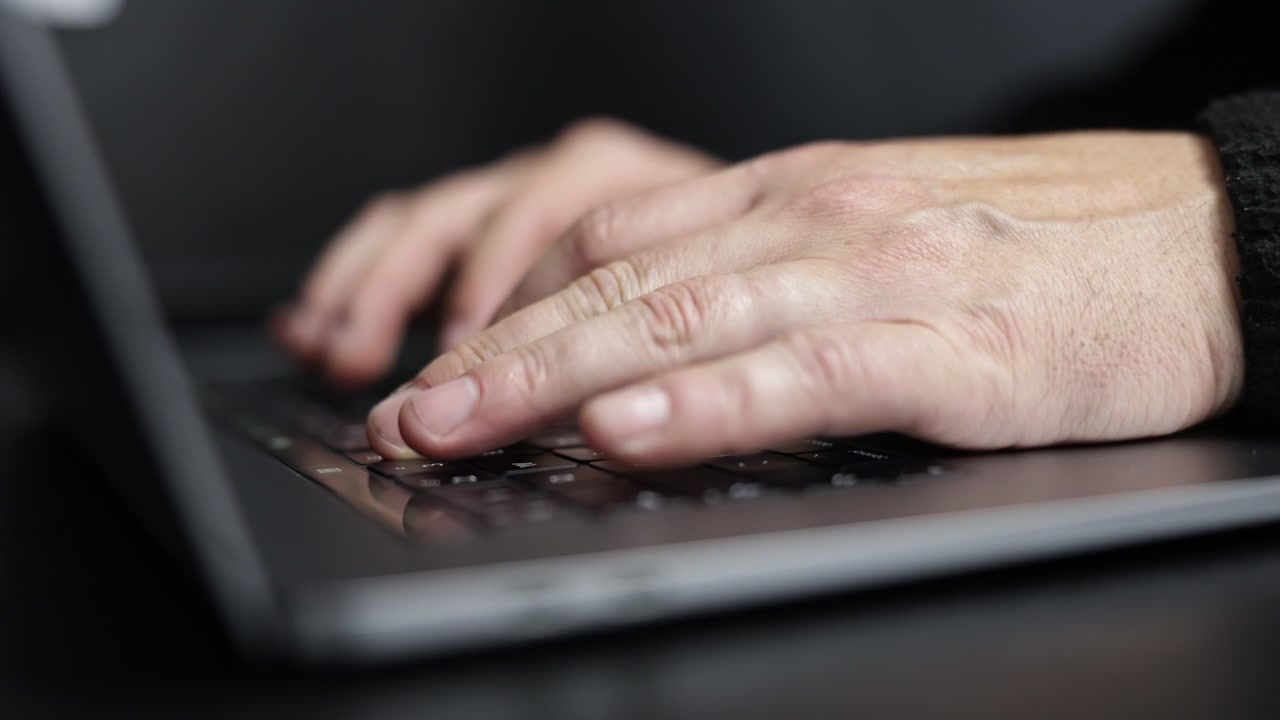 Detailed cinematic close-up of hands typing on a laptop keyboard, capturing focused work, digital communication, and modern technology in a professional workspace setting.
