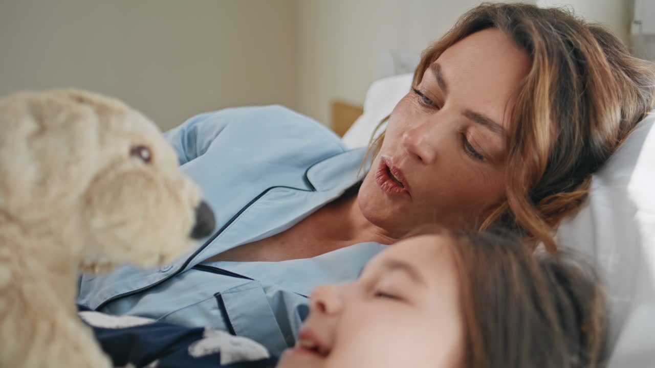 Biancheria da letto bambino madre che gioca con un giocattolo sdraiati primo piano. Mattina pigra di una famiglia spensierata