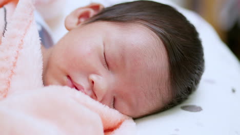 panning on a close-up shot of an adorable newborn baby sleeping peacefully on her crib as she is wrapped in her cottony blanket