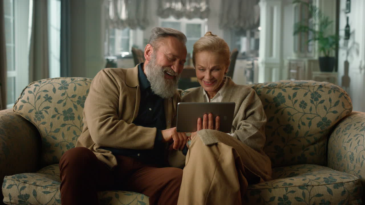 Happy senior old couple talking on video call using digital tablet computer