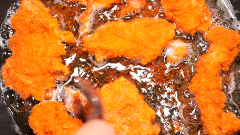 crispy breaded pork cutlets frying in a pan