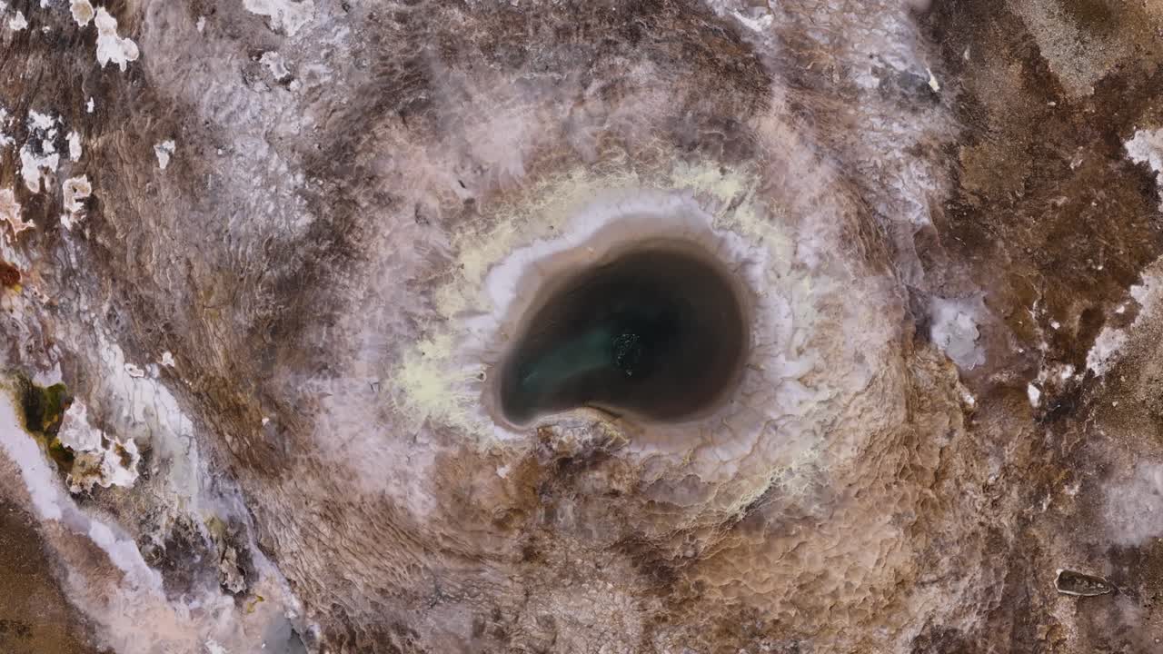 Aerial drone shot looking straight down on a bubbling geothermal hot spring in the middle of Iceland