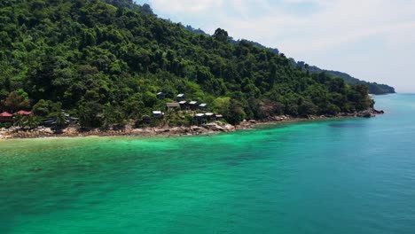 cabañas de la colina de la isla en la exuberante jungla bosques, aguas esmeraldas laguna