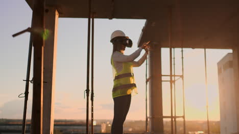 Inspectora-Con-Gafas-Vr-Y-Casco-Comprueba-El-Progreso-De-La-Construcción-De-Un-Rascacielos-Moviendo-Sus-Manos-Al-Atardecer-Visualizando-El-Plano-Del-Edificio