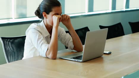 ejecutivo llorando mientras trabaja en la computadora portátil en la sala de conferencias