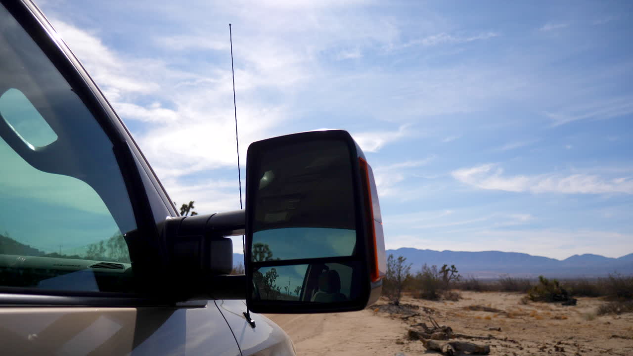 con vistas al pintoresco paisaje desértico de california y al cielo azul junto a un espejo retrovisor de una camioneta en un viaje de campamento