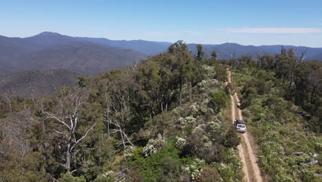 Tiro-De-Drone-De-Toyota-4wd-Conduciendo-En-El-Monte-Con-Montañas-En-El-Fondo-Cerca-Del-Lago-Eildon,-Victoria-Australia