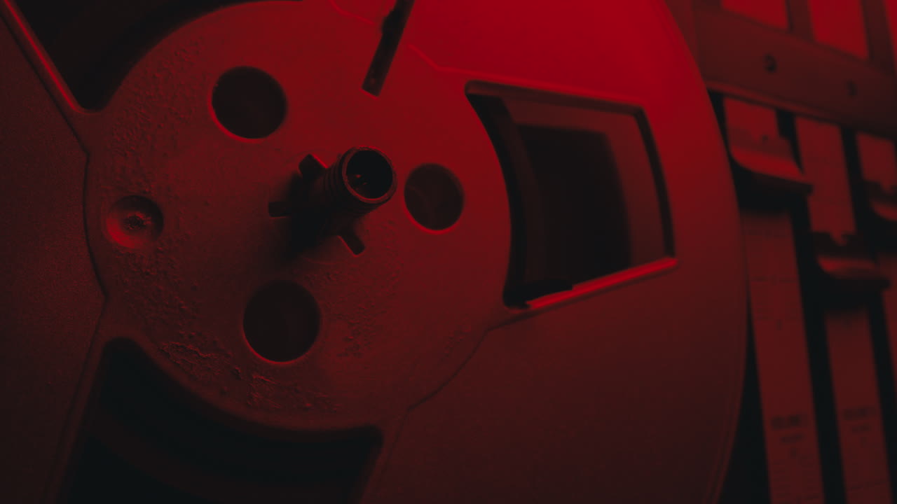 A close-up on a vintage tape recorder in a red blinking light