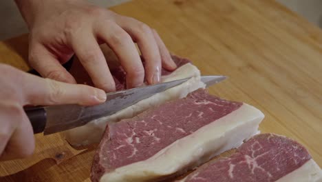 close up on chef's hands forming up stakes on wooden cut board