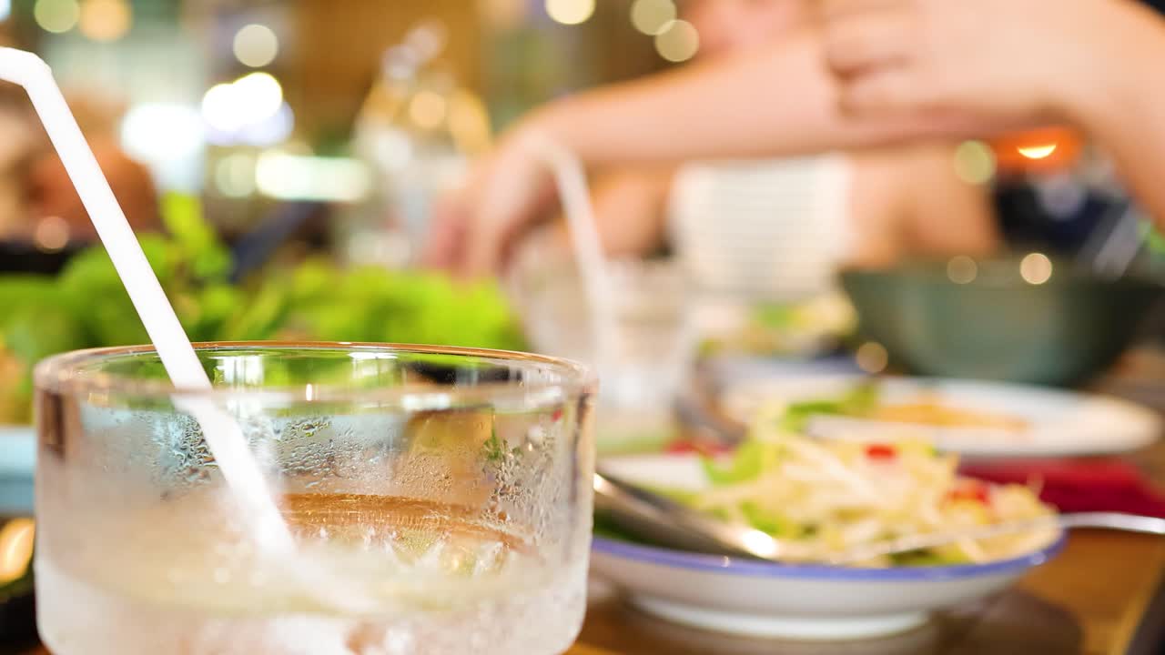 Diners enjoy a vibrant meal with fresh ingredients and iced drinks in a bustling Vietnamese restaurant setting