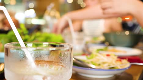 diners enjoy a vibrant meal with fresh ingredients and iced drinks in a bustling vietnamese restaurant setting