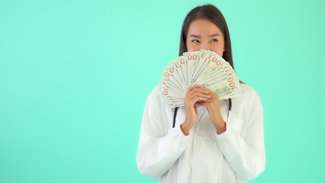 Female Doctor Smiling Holding Up Paper Banknote Money. Copy Space