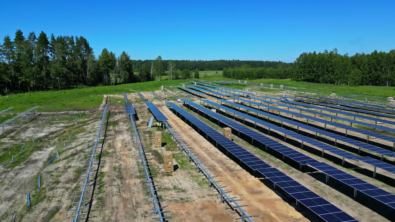 PV panels being set-up in long rows on solar farm in daytime, aerial