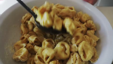 italian chef mixing homemade tortelloni pasta with parmigiano reggiano cheese