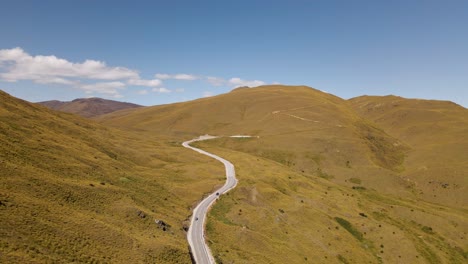 vista aérea del paso de montaña curvo a través de colinas doradas en un día soleado