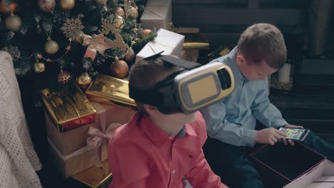 boy experiences vr game while brother plays on smartphone