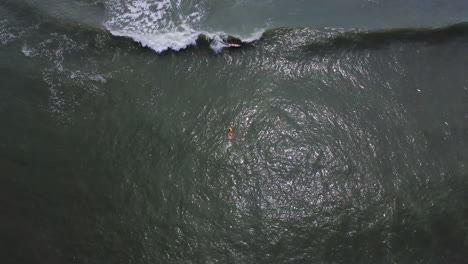 Aerial-top-view-of-girl-in-bikini-on-surfboard-and-backwards-over-a-man-surfing-a-wave