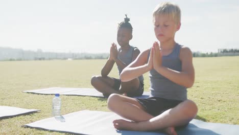 video of focused diverse boys practicing yoga on mats on sunny day