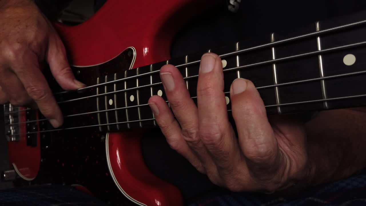primer plano medio de los dedos tocando el bajo eléctrico mostrando el posicionamiento de la mano derecha