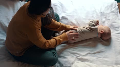 young woman massaging baby boy at home. happy woman playing with little kid