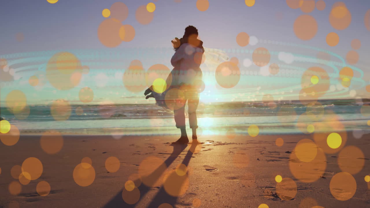 Embracing on beach, couple with glowing bokeh lights overlaying sunset animation