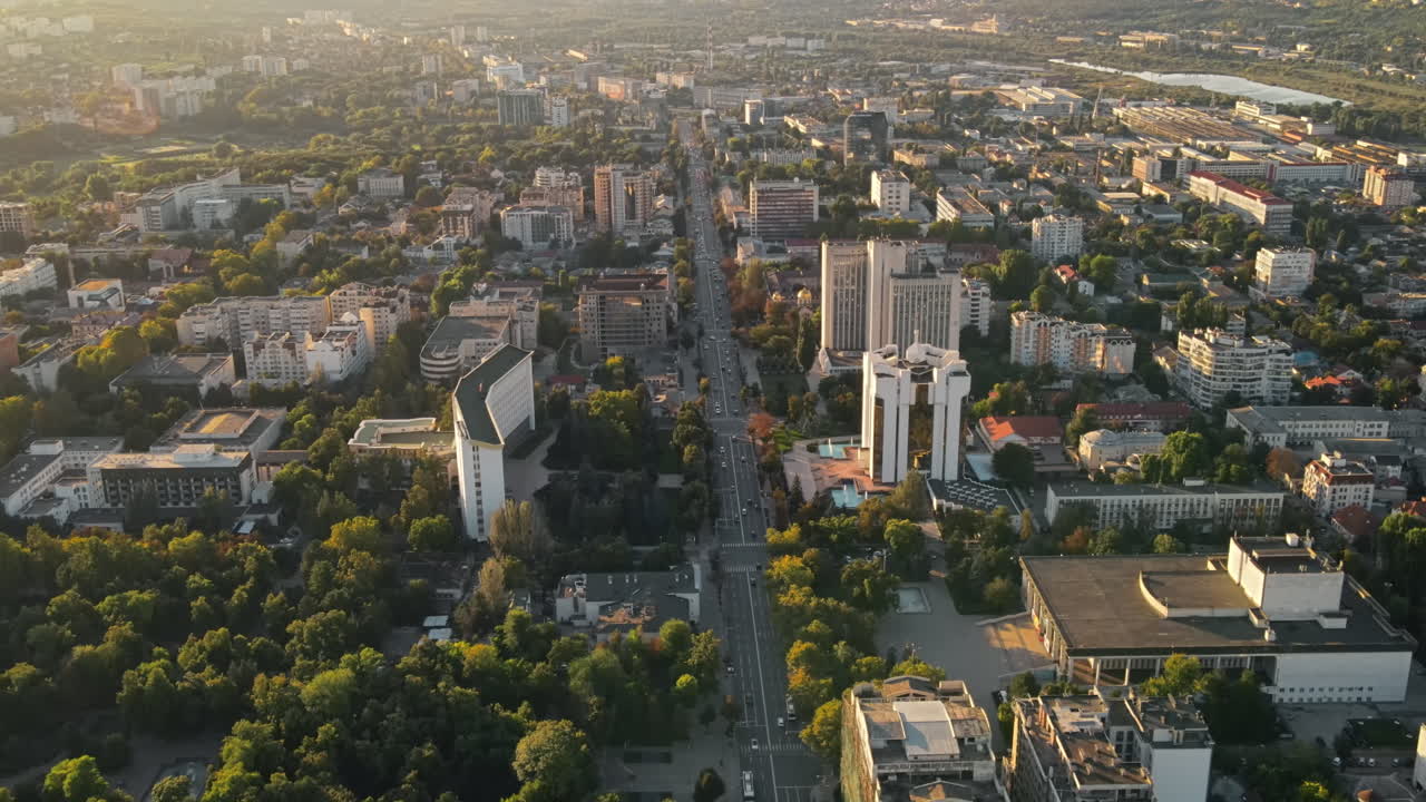Aerial drone view of Chisinau downtown at sunset. Panorama view of multiple buildings, Parliament, Presidency, roads with moving cars and lush trees. Moldova