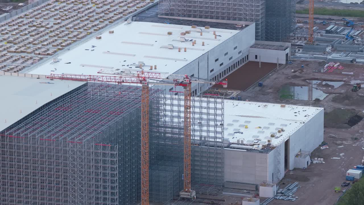 Cantiere edile aereo all'alba, gru che inquadra un nuovo centro di distribuzione.