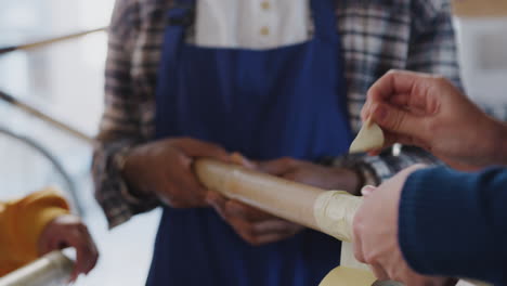 Close-Up-Of-Multi-Cultural-Team-In-Workshop-Assembling-Hand-Built-Sustainable-Bamboo-Bicycle-Frame