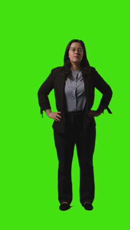 vertical video full length shot of businesswoman wearing glasses and suit standing against green screen