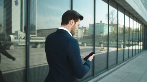 Rückansicht-Geschäftsmann-Geht-Mit-Telefon.-Mann-Benutzt-Smartphone-Im-Freien