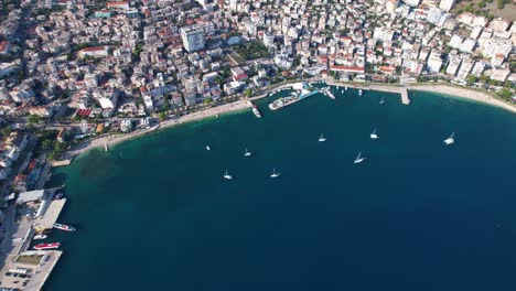 vista aérea de la bahía de saranda: puerto, barcos anclados, mar azul y barco hundido en este pintoresco destino turístico