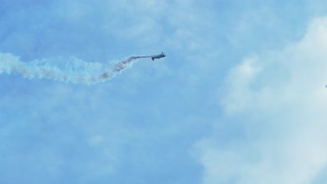 sukhoi su-26 aerobatic airplane carrying out dynamic maneuvers in front of spectators at baltic airshow in liepaja, latvia, white smoke trails, handheld tracking shot, 4k