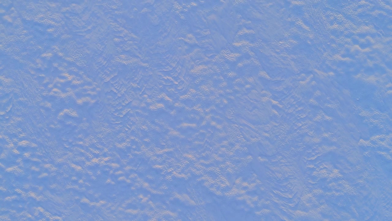 Aerial texture of wind patterned snow on frozen lake surface, Lapland, Finland. Overhead drone shot of pale blue and beige rippled ice with subtle wind erosion marks filling the entire frame.