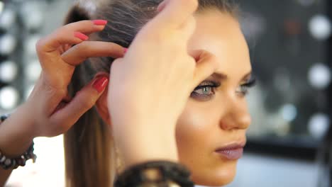 Close-up-shot-of-a-makeup-artist's-hands-applying-golden-shiny-pieces-of-metallic-paper-on-a-model's-face.-Preparing-for-the