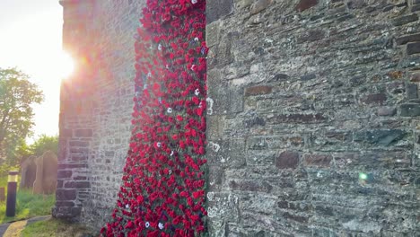 giant poppy remembrance wreath stretching up church wall at sunset as camera pans up revealing tall building with cloudy sky. part of ve day commemorations.