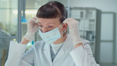 portrait of female scientist putting on mask and glasses in lab