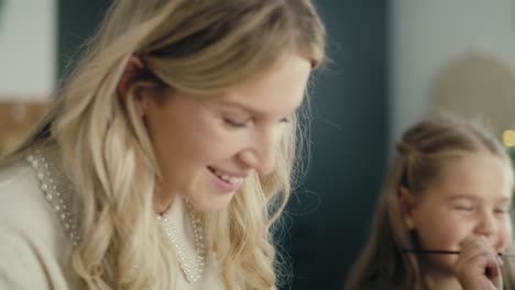 caucasian woman and daughter decorating cone with white paint.