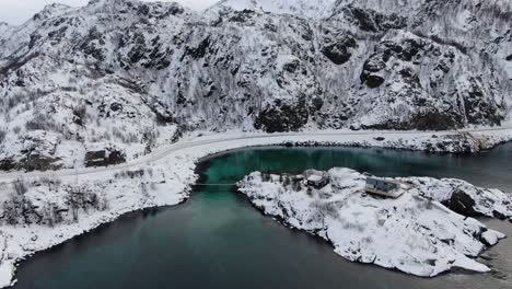 vista del avión no tripulado en el área de tromso en invierno volando sobre un puente colgante de madera a una isla con un mar azul claro en noruega