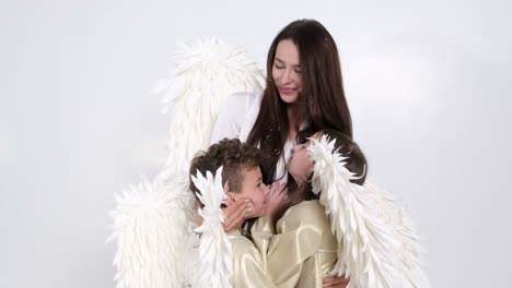 A mother embraces her two children in angel costumes