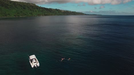 vista aérea estática sobre personas buceando en el mar tropical en barco y cerca de la costa de la isla tropical