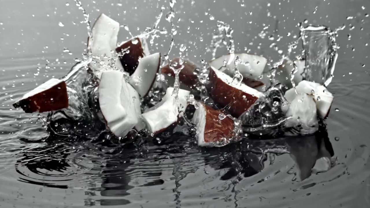 Pezzi di cocco freschi che si tuffano nell'acqua al rallentatore